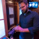Man inspecting a puzzle device during a train-themed escape game at Escapology.
